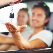 blurred couple with man receiving car key from salesman