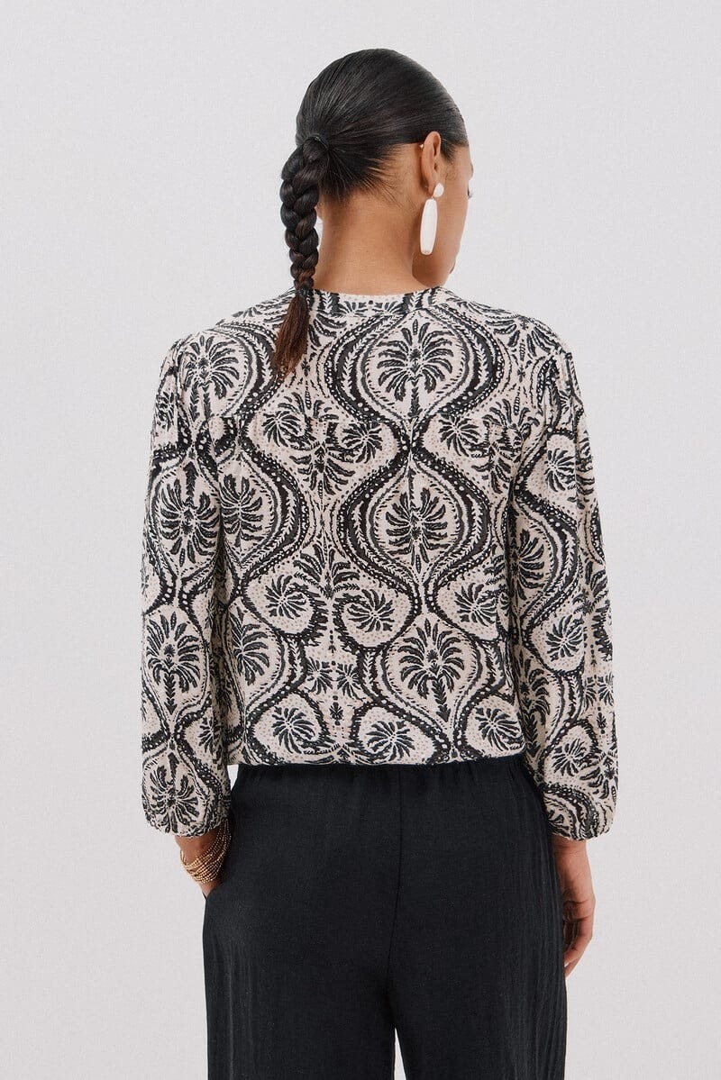 woman wearing a patterned blouse and dark pants