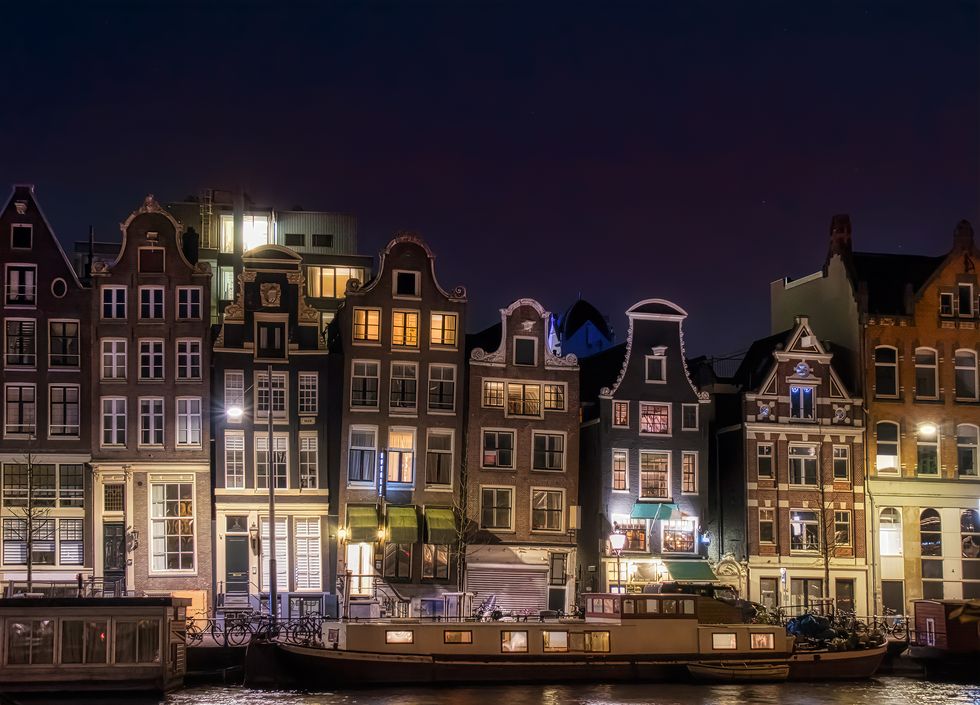 typical houses by the river amstel in the central part of amsterdam, at night
