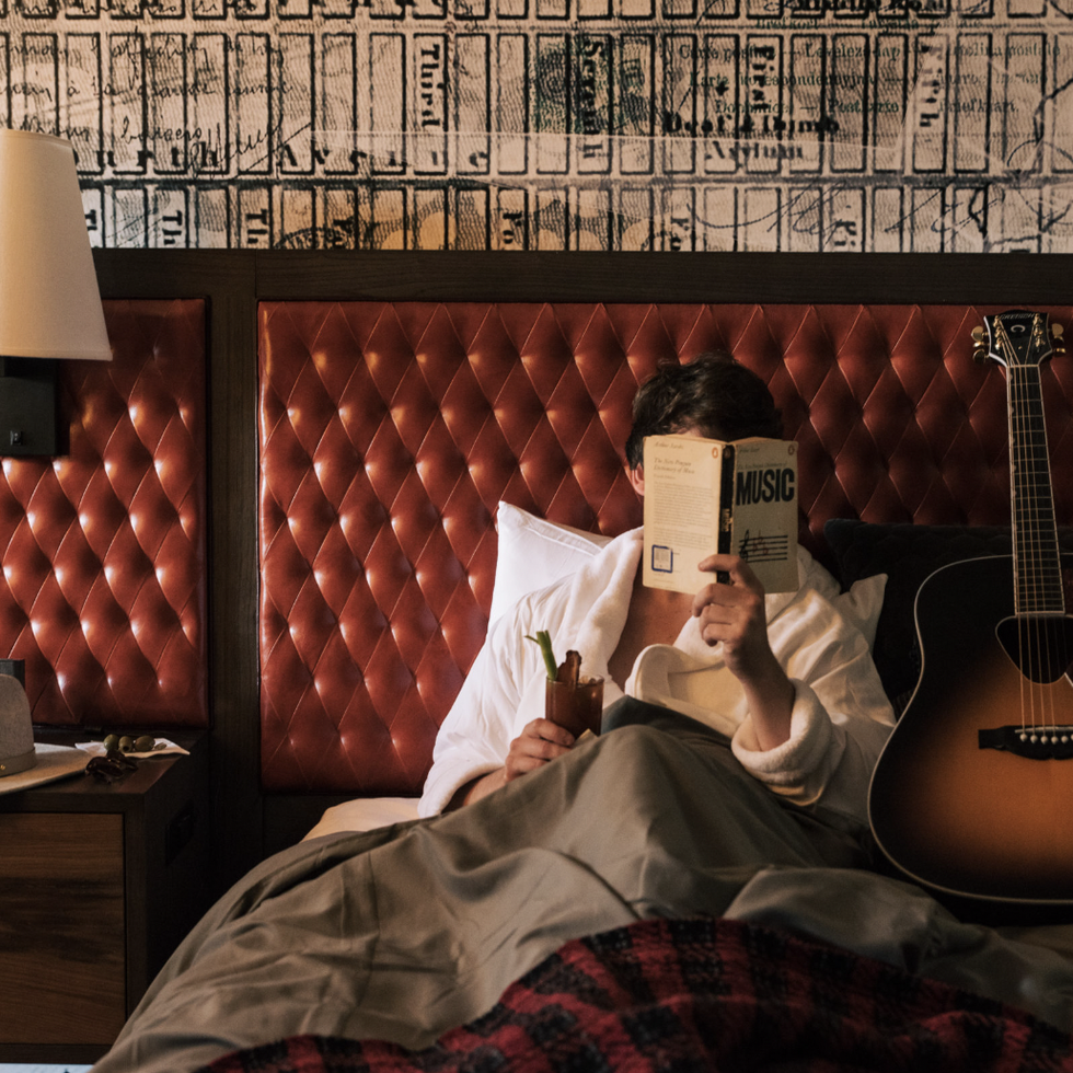a person lying in bed with a book and a guitar