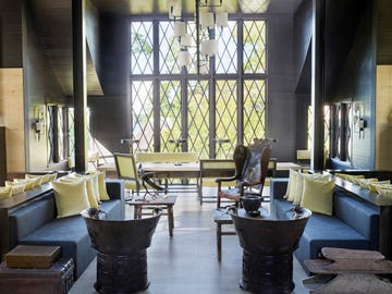 dining alcove with black walls and tall windows and walls and a table with green upholstered chairs