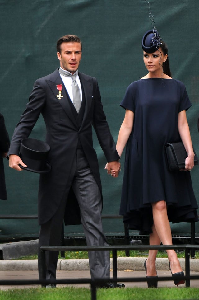 Victoria Beckham asiste a la boda de Kate Middleton en 2011 embarazada con vestido azul marino suelto y tocado