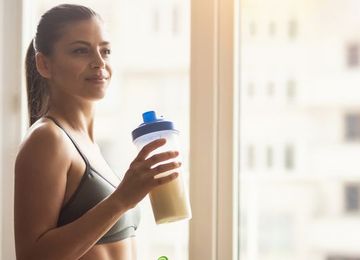 Bodybuilder girl relax after exhausting training, Young athlete drinking sports drink after workout, beautiful woman resting after exercising training.