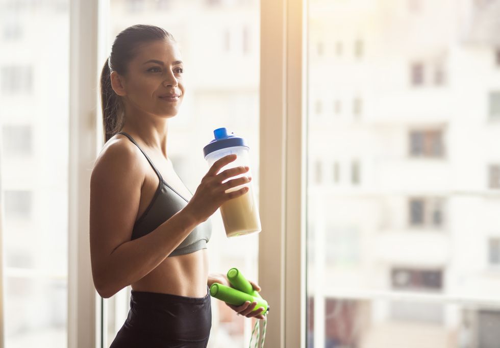 bodybuilder girl relax after exhausting training, young athlete drinking sports drink after workout, beautiful woman resting after exercising training