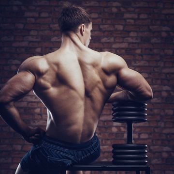 bodybuilder strong man pumping up back muscles