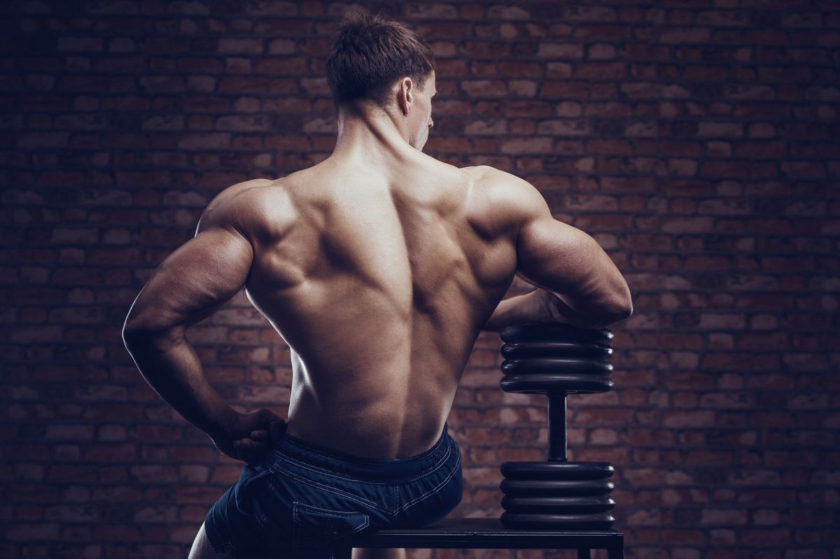 bodybuilder strong man pumping up back muscles
