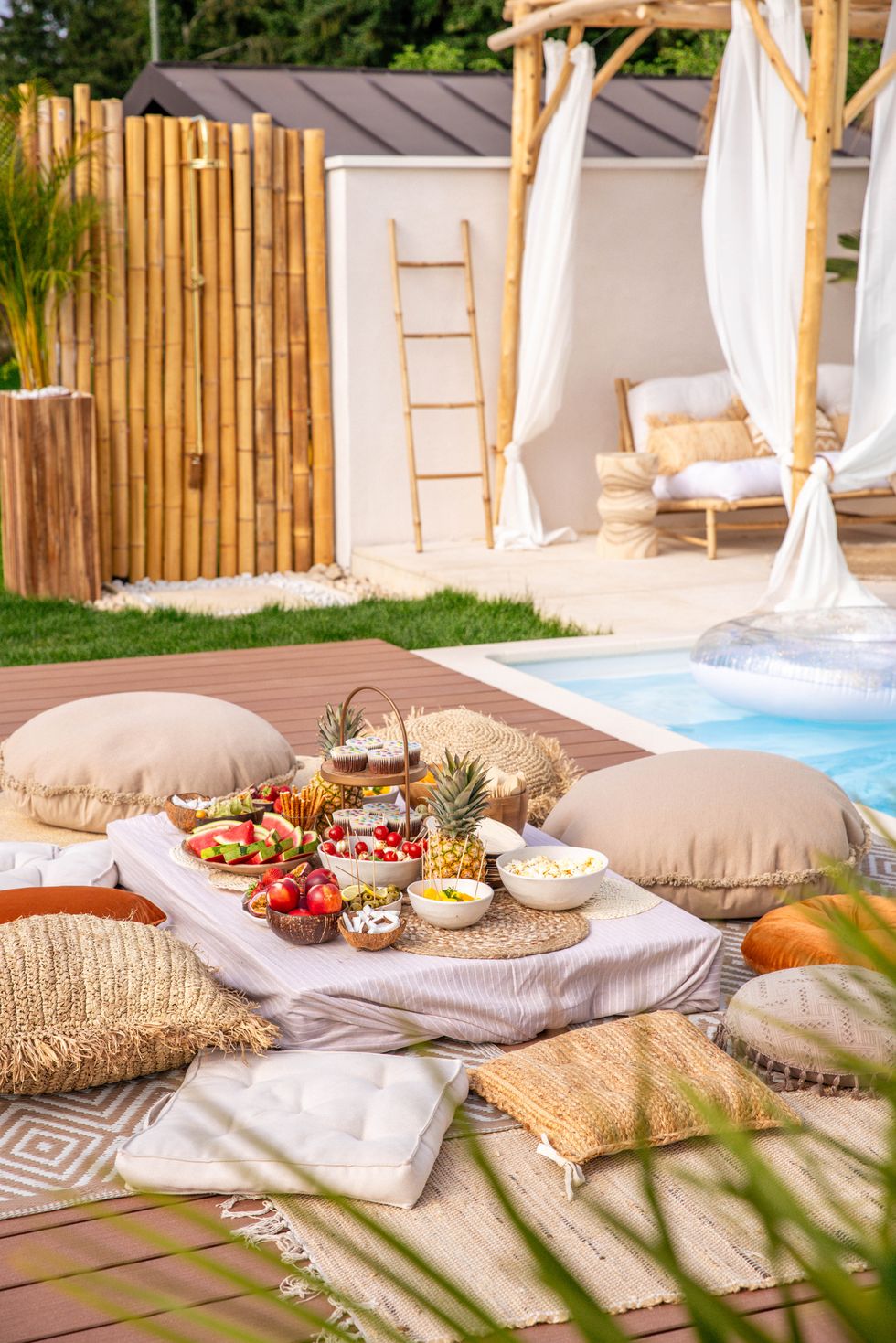boho garden party picnic by the swimming pool on wood patio with food buffet and cushions