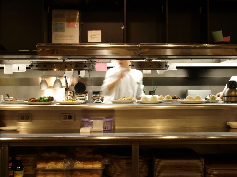 cook filling orders at all night diner with several plates of food ready to be picked up by servers