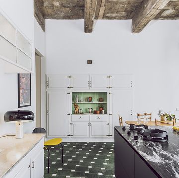 una cocina de campo con vigas de madera y suelo de azulejos verdes