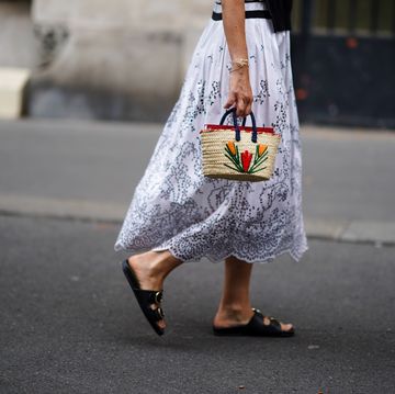 mujer con vestido bordado, sandalias con hebilla y cesta mini bordada