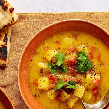 overhead shot of two bowls of potato soup with some naan bread