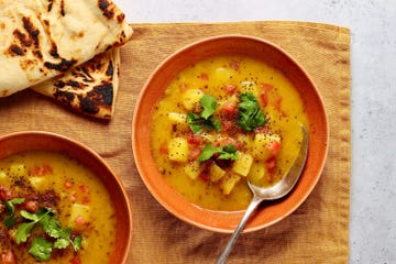 overhead shot of two bowls of potato soup with some naan bread