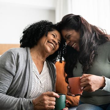 mother and daughter laughing together while having coffee