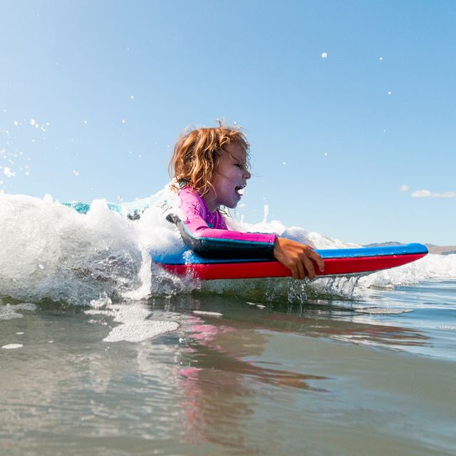 young girl boogie boarding in ocean