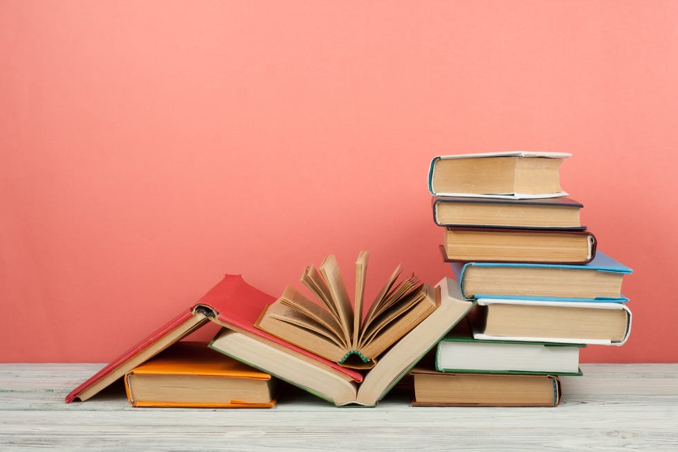 Book stacking. Open book, hardback books on wooden table and pink background. Back to school. Copy space for text