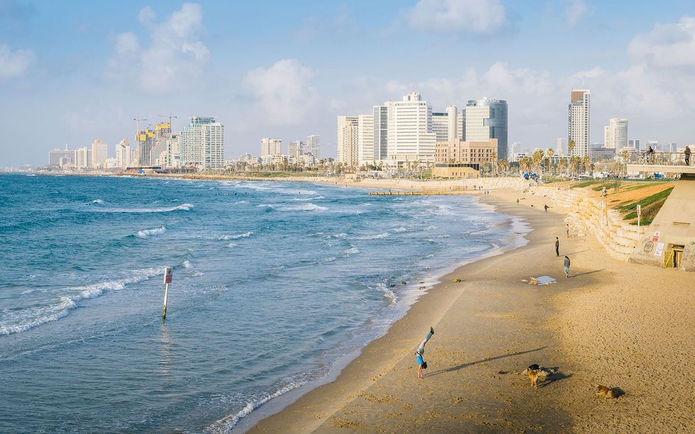 Een mediterraan zandstrand strekt zich uit onder de stedelijke skyline van Tel Aviv waar startups van wereldklasse naast toegankelijke eigentijdse kunst en een bijzonder culinair aanbod zijn te vinden