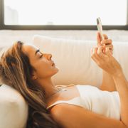 bored woman laying on sofa with smartphone, wasting time online, procrastination with gadgets