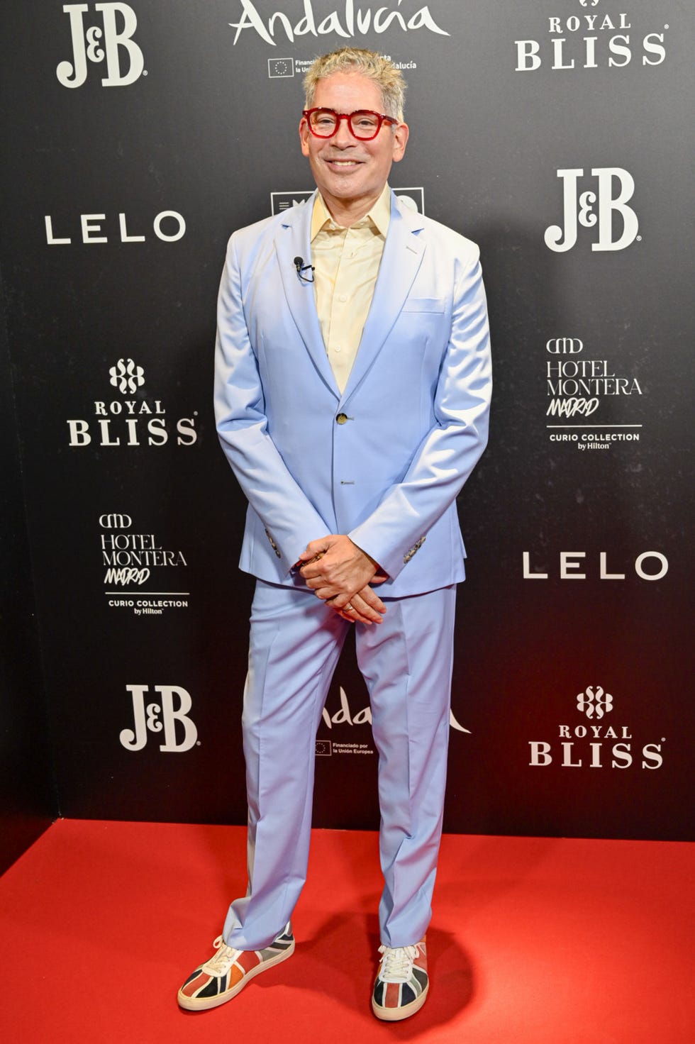 el presentador con un traje azul y gafas rojas