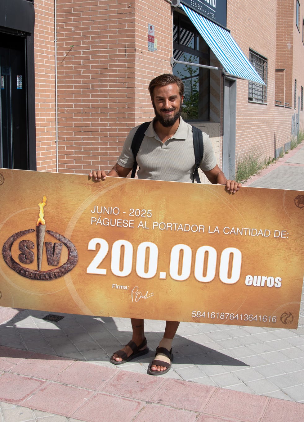 borja gonzalez posa con su cheque de supervivientes a su salida de un restaurante
