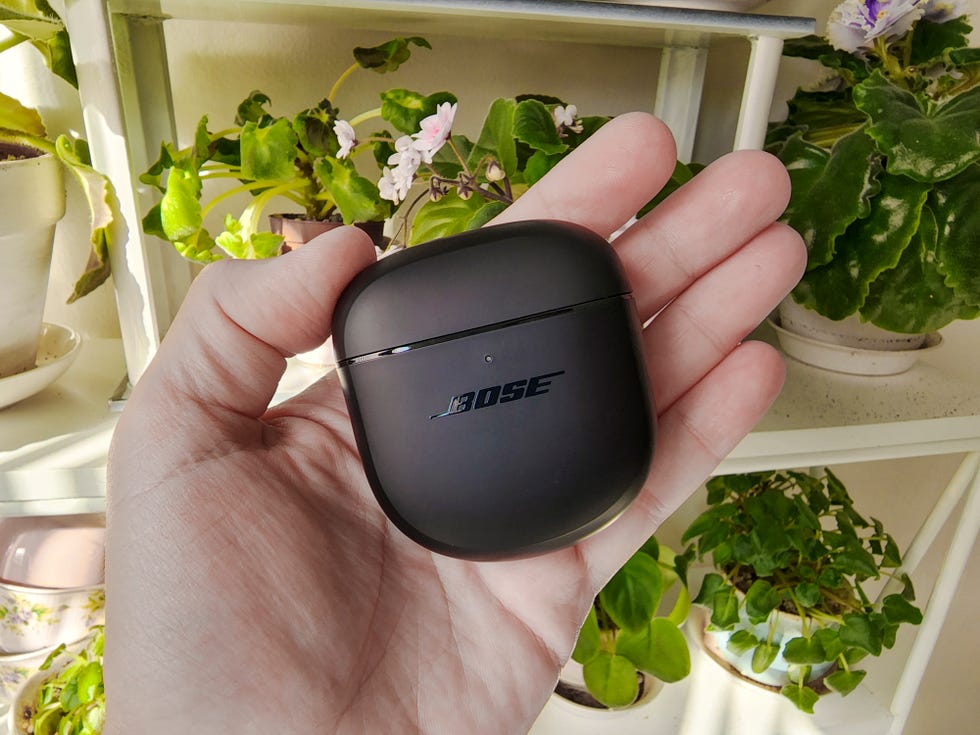 holding bose quietcomfort earbuds in hand