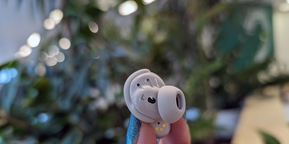 a person holding a small true wireless earbud inside view