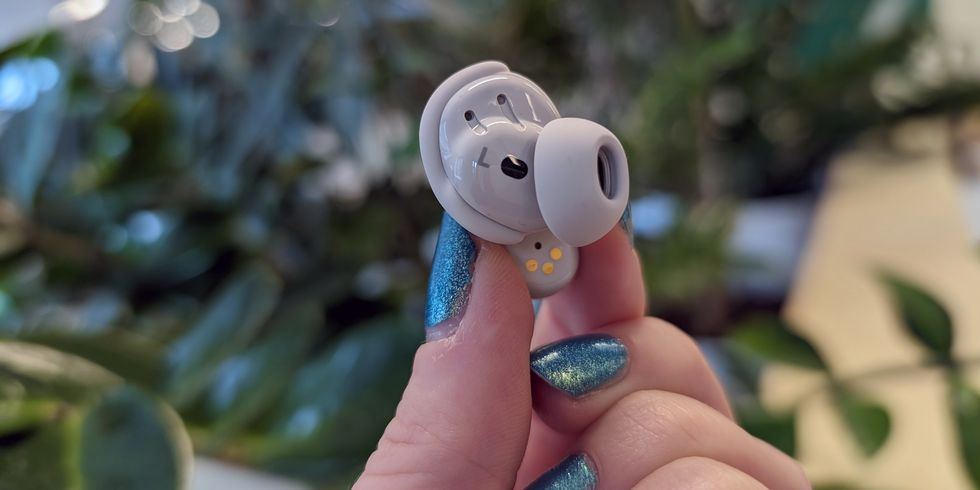 a person holding a small true wireless earbud inside view