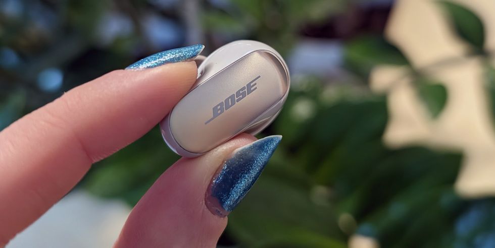 a person holding a small bose earbud