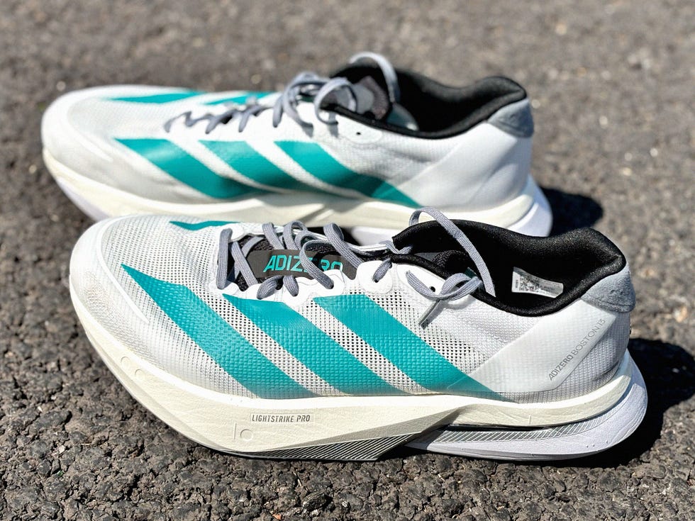 a pair of white Adidas exclusive running shoes with blue stripes