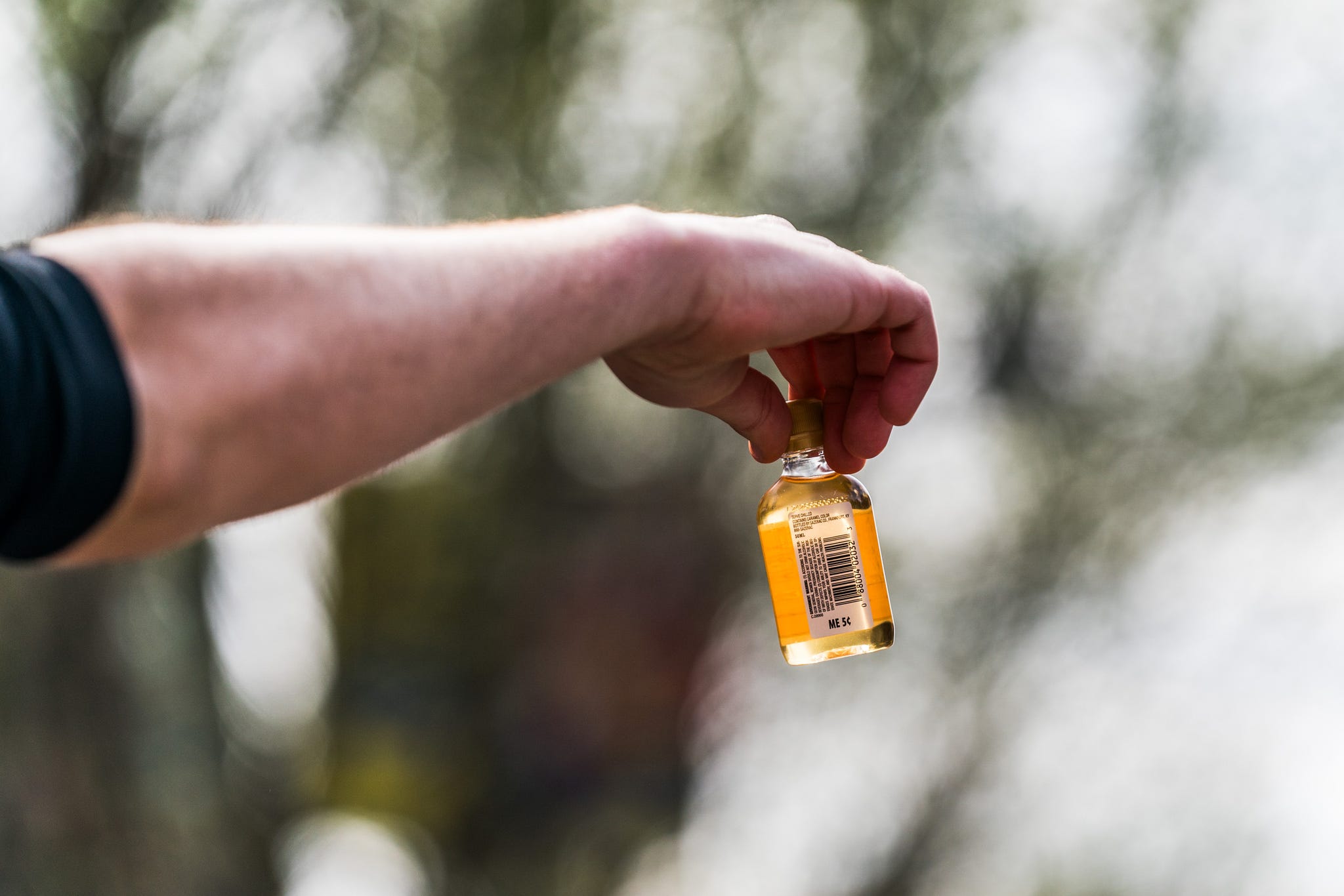 a person holding a small bottle of alcohol