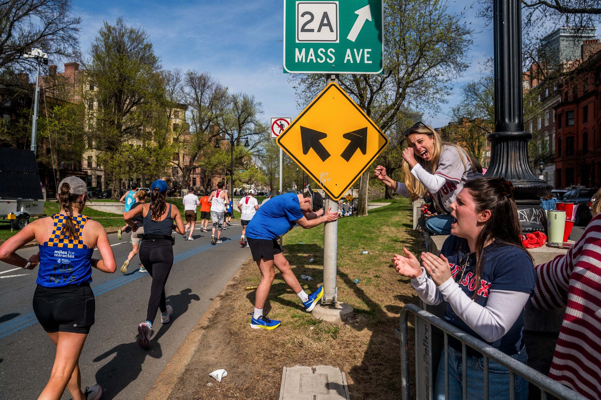 a runner stretches as other runners pass him and spectators cheer on