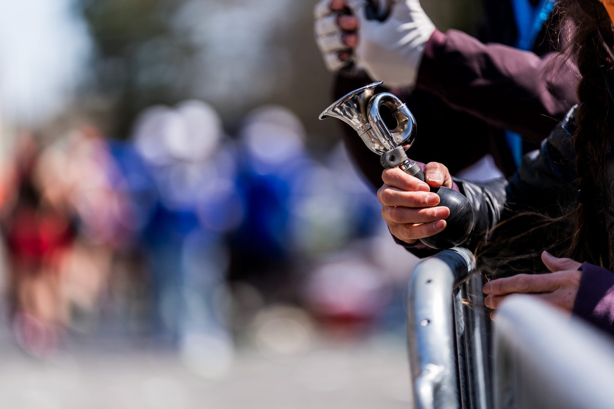 A hand holding a small trumpetlike instrument at a crowded event