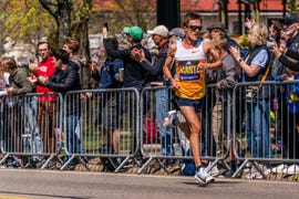 a runner competing in a marathon with enthusiastic spectators cheering along the route mantz boston marathon 2025