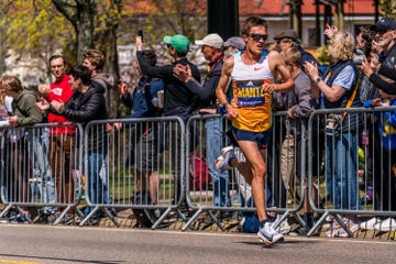 a runner competing in a marathon with enthusiastic spectators cheering along the route mantz boston marathon 2025