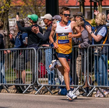 RWD a runner competing in a marathon with enthusiastic spectators cheering along the route mantz boston marathon 2025