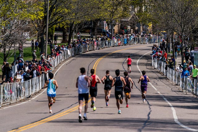 competitors in a race running along a curved road surrounded by spectators