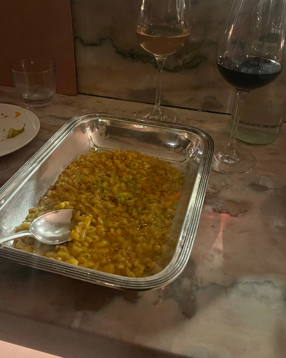 a serving dish of risotto with two glasses of wine on a table