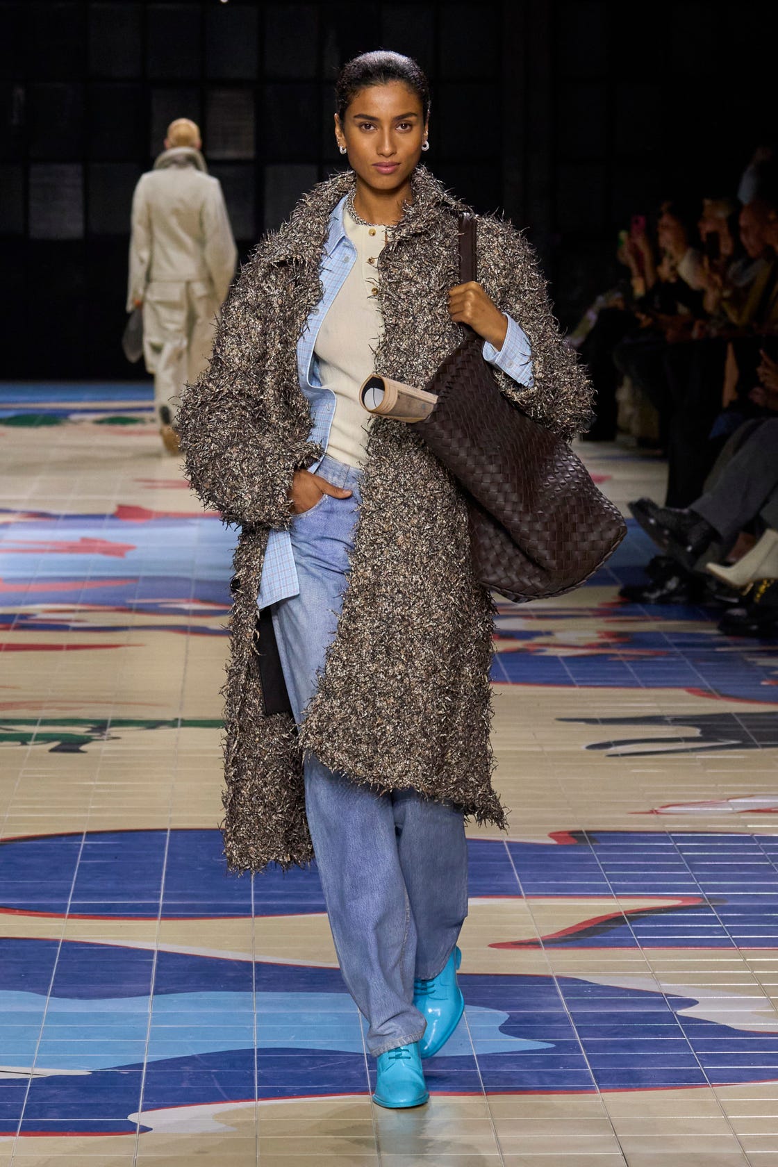 a person wearing a coat and boots with a travel tote bag