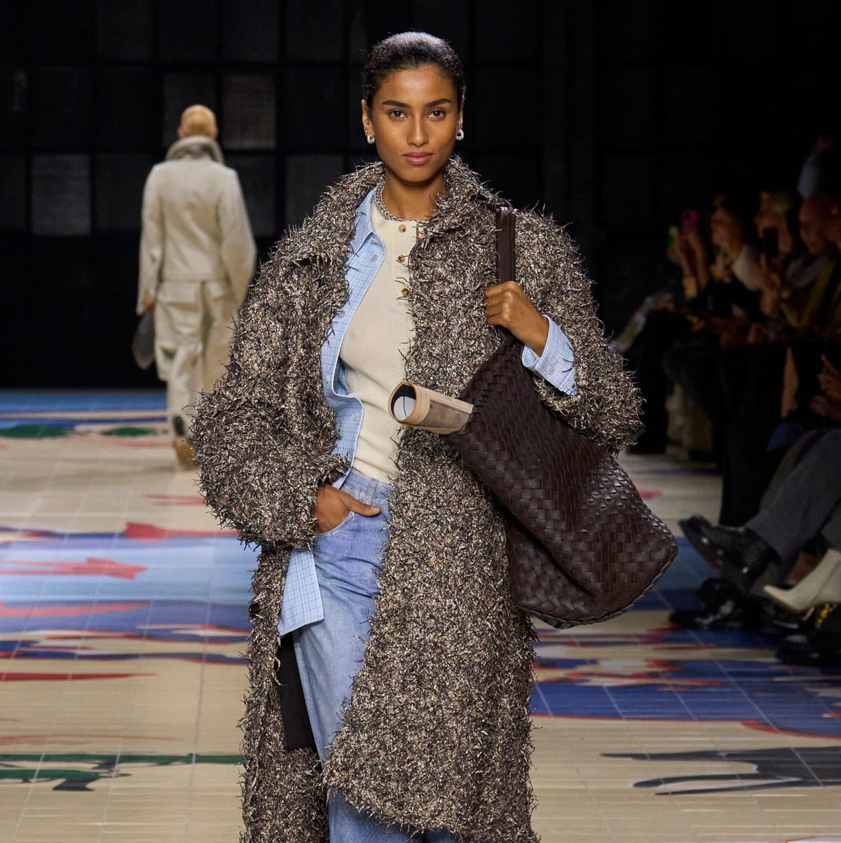 a person wearing a coat and boots with a travel tote bag