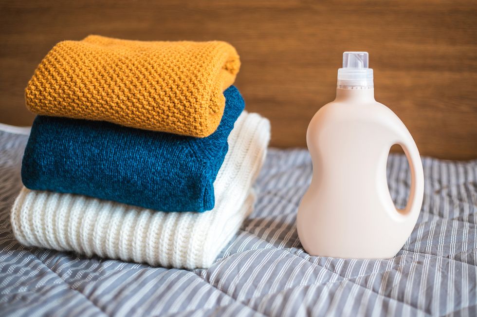 Bottle of detergent and a pile of sweaters.
