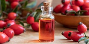 A bottle of rose hip seed oil with fresh rose hips