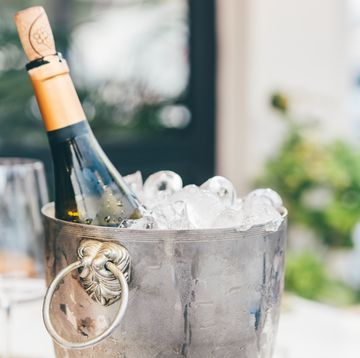 bottle of wine in ice bucket with wine glasses.