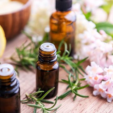 bottles of essential oil with herbs and fruits on wooden table rosemary, lemon and flowers