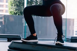 bottom part of fitness woman in sportswear doing deep squat at gym