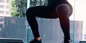 bottom part of fitness woman in sportswear doing deep squat at gym