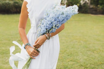 bouquet of blue delphinium flowers in bride's hands close up bijouterie bracelets on hands