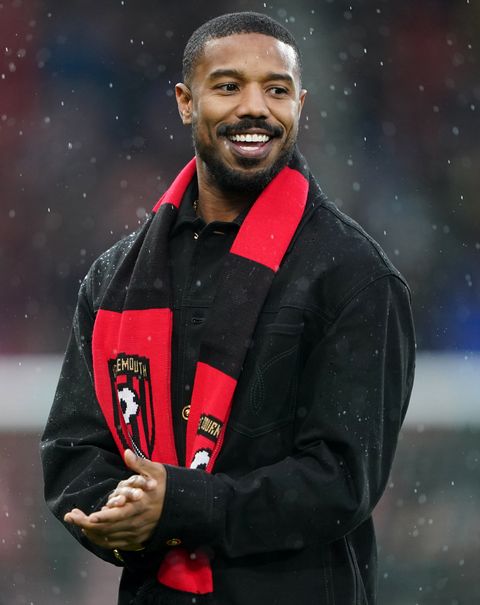 michael b jordan clapping and smiling while wearing a bournemouth scarf
