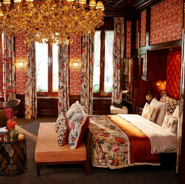 a red bedroom with a chandelier bed and chairs