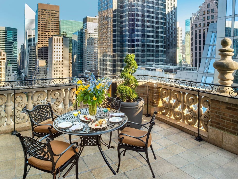 a terrace with table and chairs and a city skyline in the background