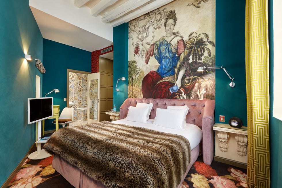 a bedroom with a large bed and painting at hotel du petit moulin