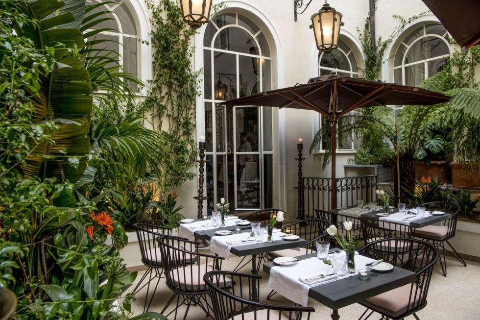 a patio with plants tables and chairs at hotel vilon